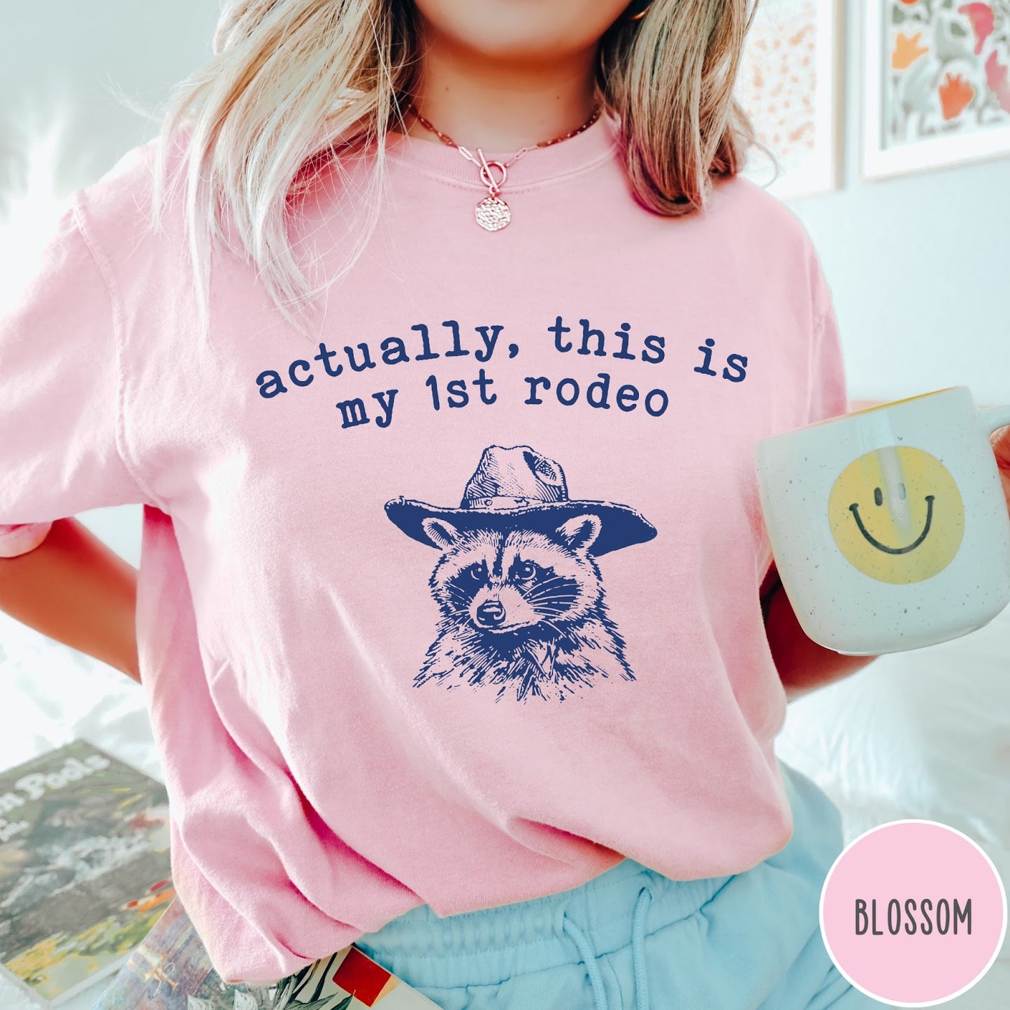 Comfort Colors tee in Blossom featuring western style graphic of a raccoon wearing a cowboy hat
