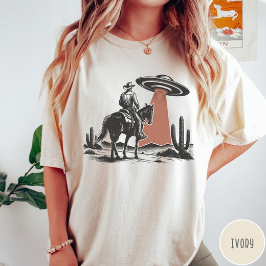 Comfort Colors tee in Ivory featuring western style graphic of a cowboy on horseback under a UFO