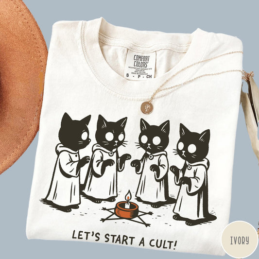 Comfort Colors tee in Ivory featuring illustrated style graphic of four cats in robes around a candle