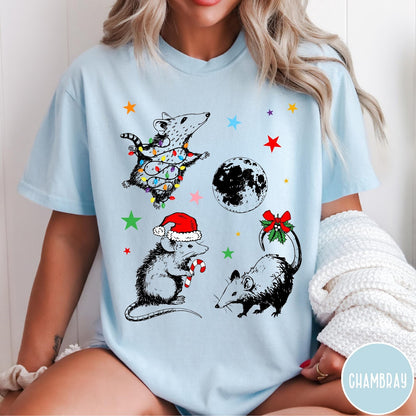 Comfort Colors tee in Chambray featuring holiday possum graphic with Christmas lights, candy cane, and moon.