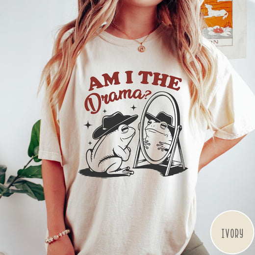 Comfort Colors tee in Ivory featuring whimsical frog graphic with a cowboy hat looking into a mirror