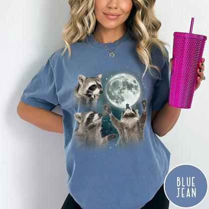 Comfort Colors tee in Blue Jean featuring artistic graphic of three raccoons reaching toward a bright full moon