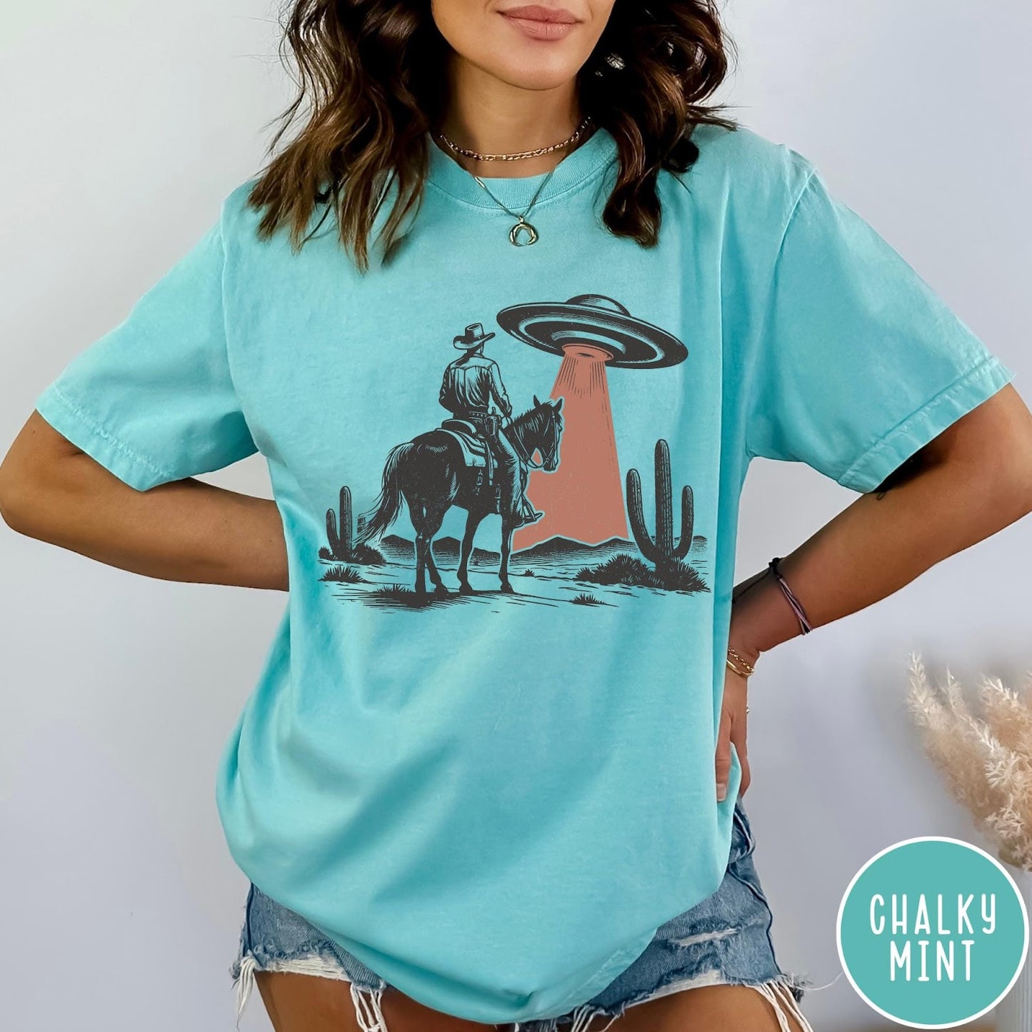 Comfort Colors tee in Chalky Mint featuring western style graphic of a cowboy on horseback under a UFO