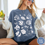 Comfort Colors tee in Blue Jean featuring coastal style graphic with various tropical fish and ocean life illustrations