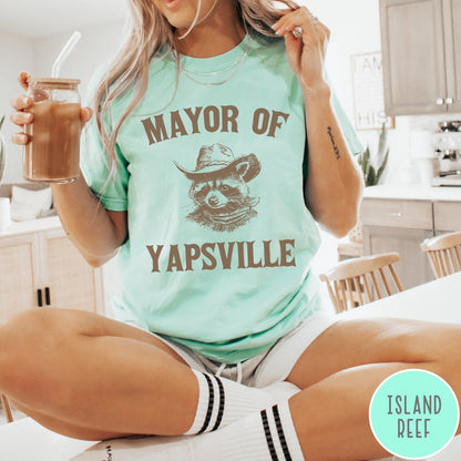 Comfort Colors tee in Island Reef featuring western style graphic of a raccoon wearing a cowboy hat and bandana