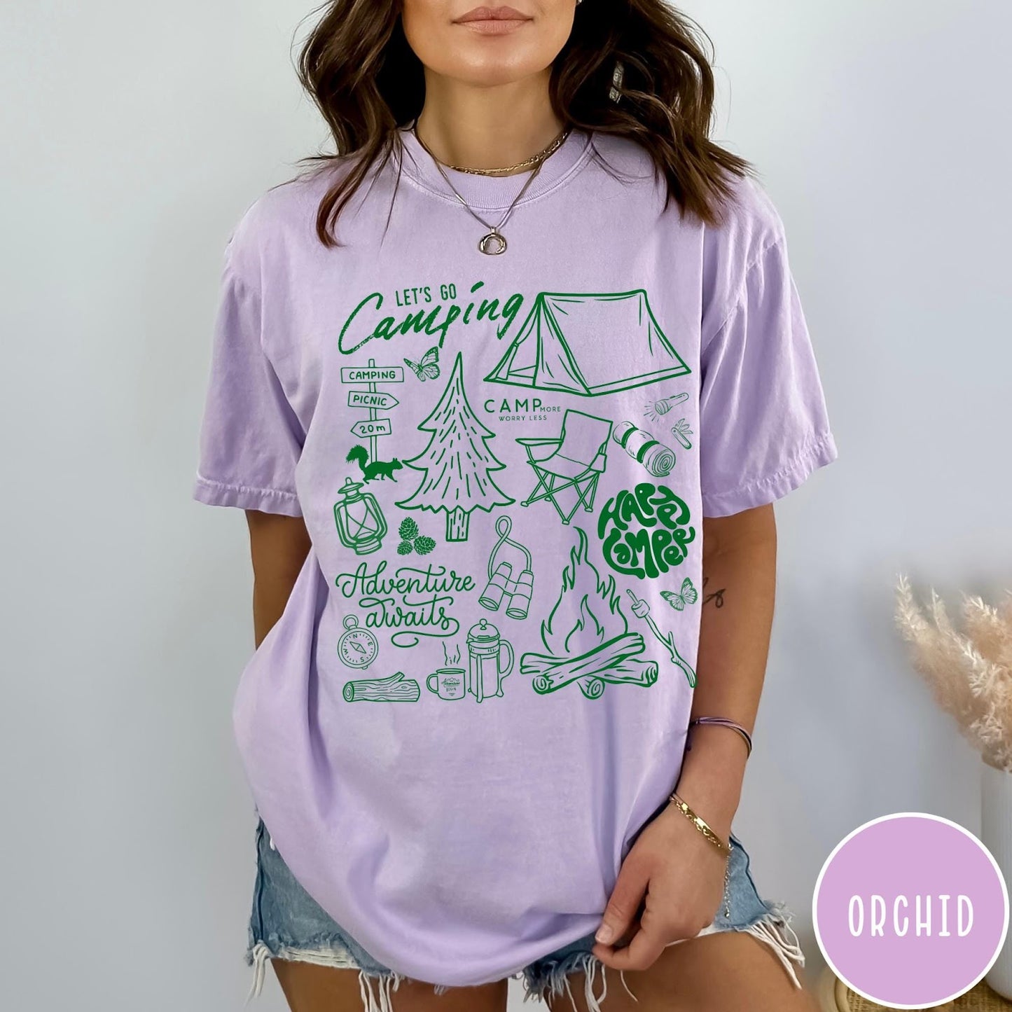 Comfort Colors tee in Orchid featuring retro camping adventure collage graphic with tent, campfire, and outdoor icons