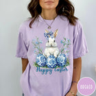 Comfort Colors tee in Orchid featuring Easter bunny graphic with blue floral bow and patterned Easter eggs