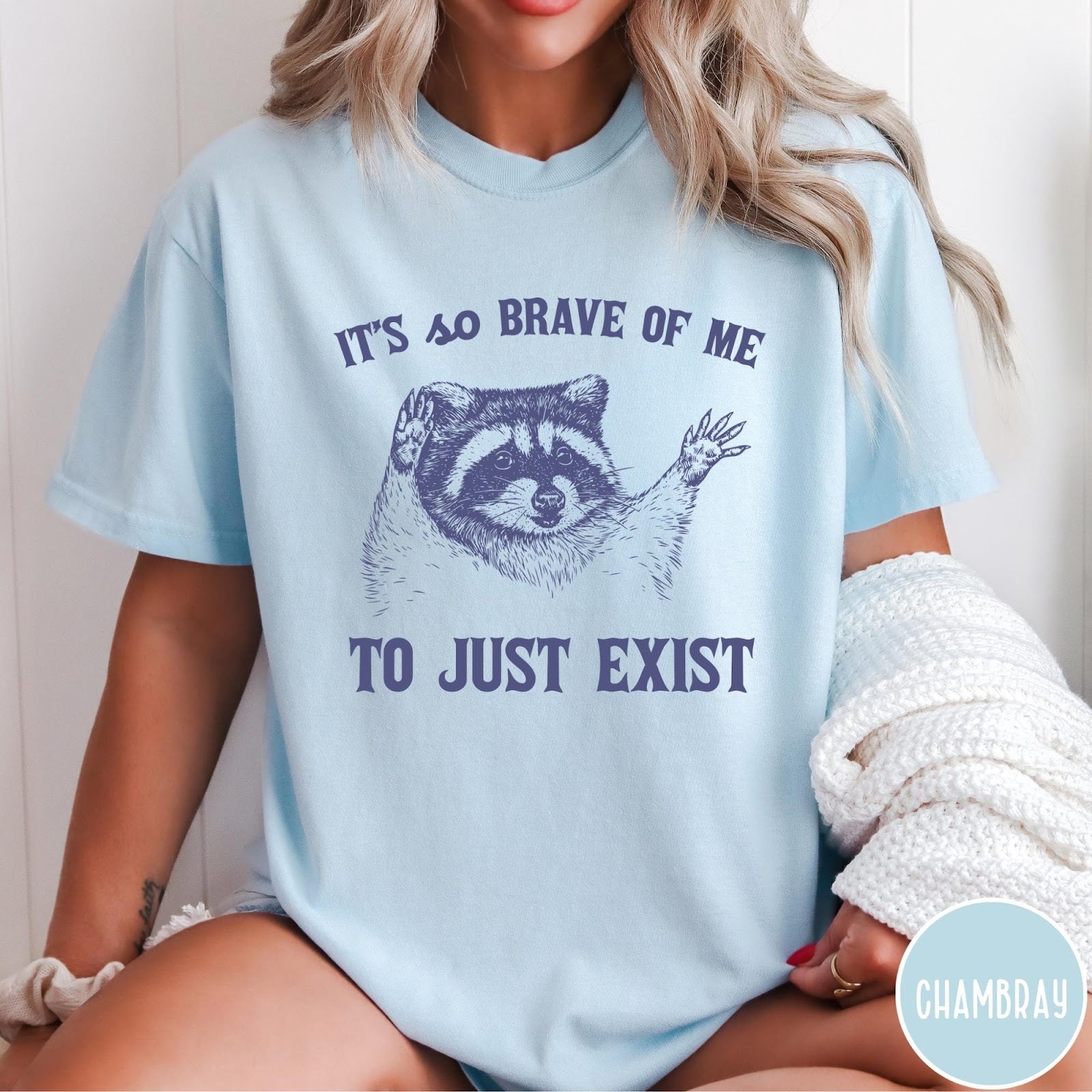 Comfort Colors tee in Chambray featuring illustrative raccoon graphic with text It's So Brave Of Me To Just Exist