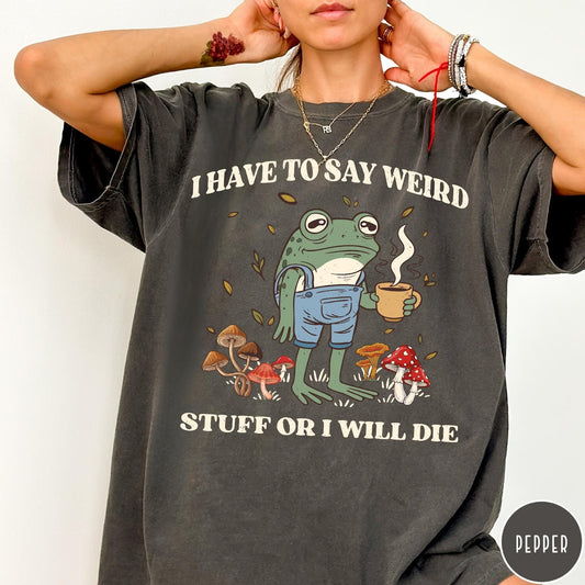 Comfort Colors tee in Pepper featuring illustrative frog graphic with coffee cup and various forest mushrooms