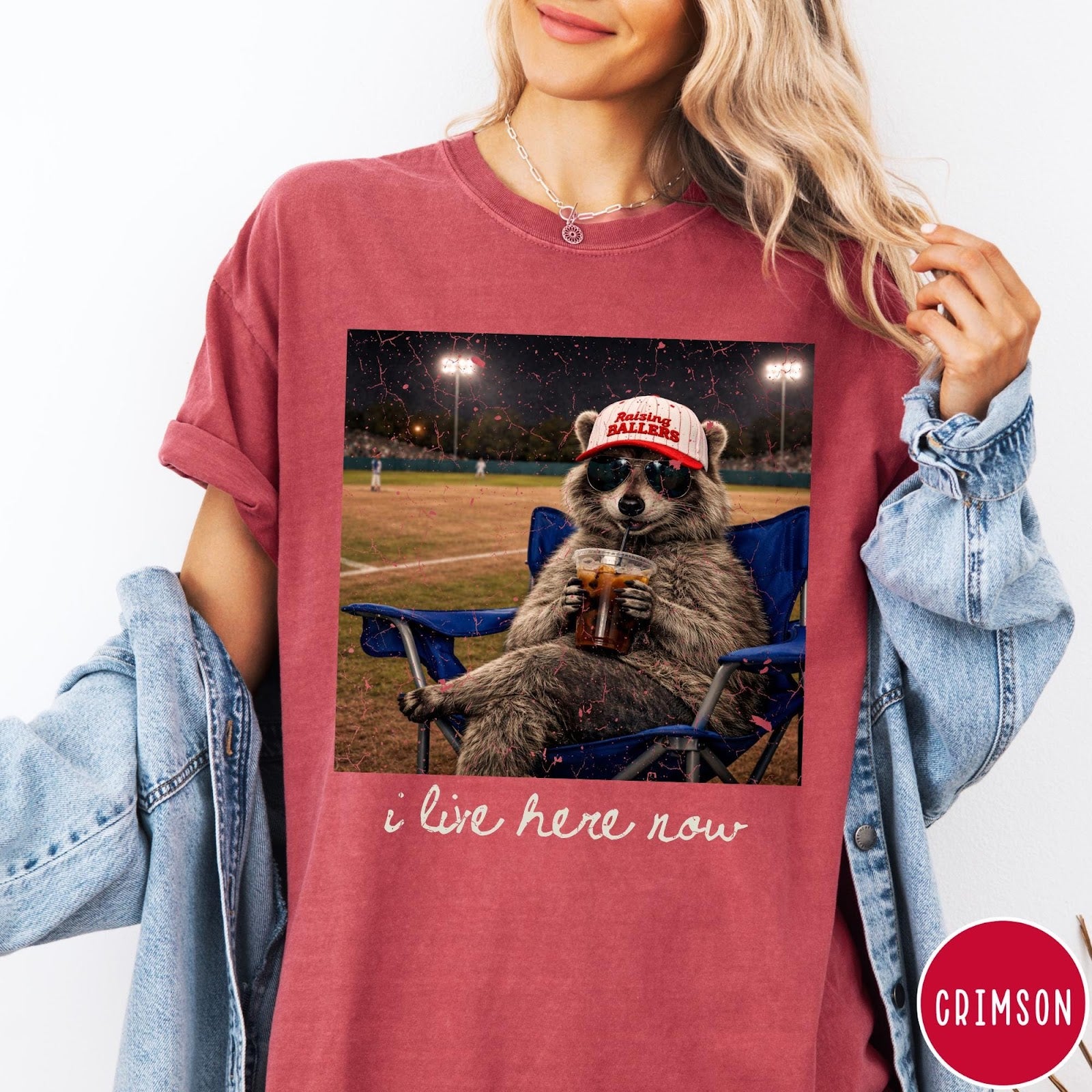 Comfort Colors tee in Crimson featuring graphic style raccoon wearing sunglasses and baseball cap at a stadium