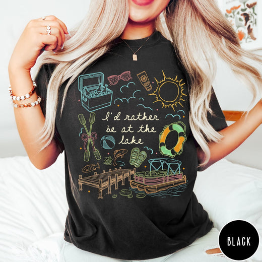 Comfort Colors tee in Black featuring lake vacation graphic with pontoon boat, dock, and summer accessories