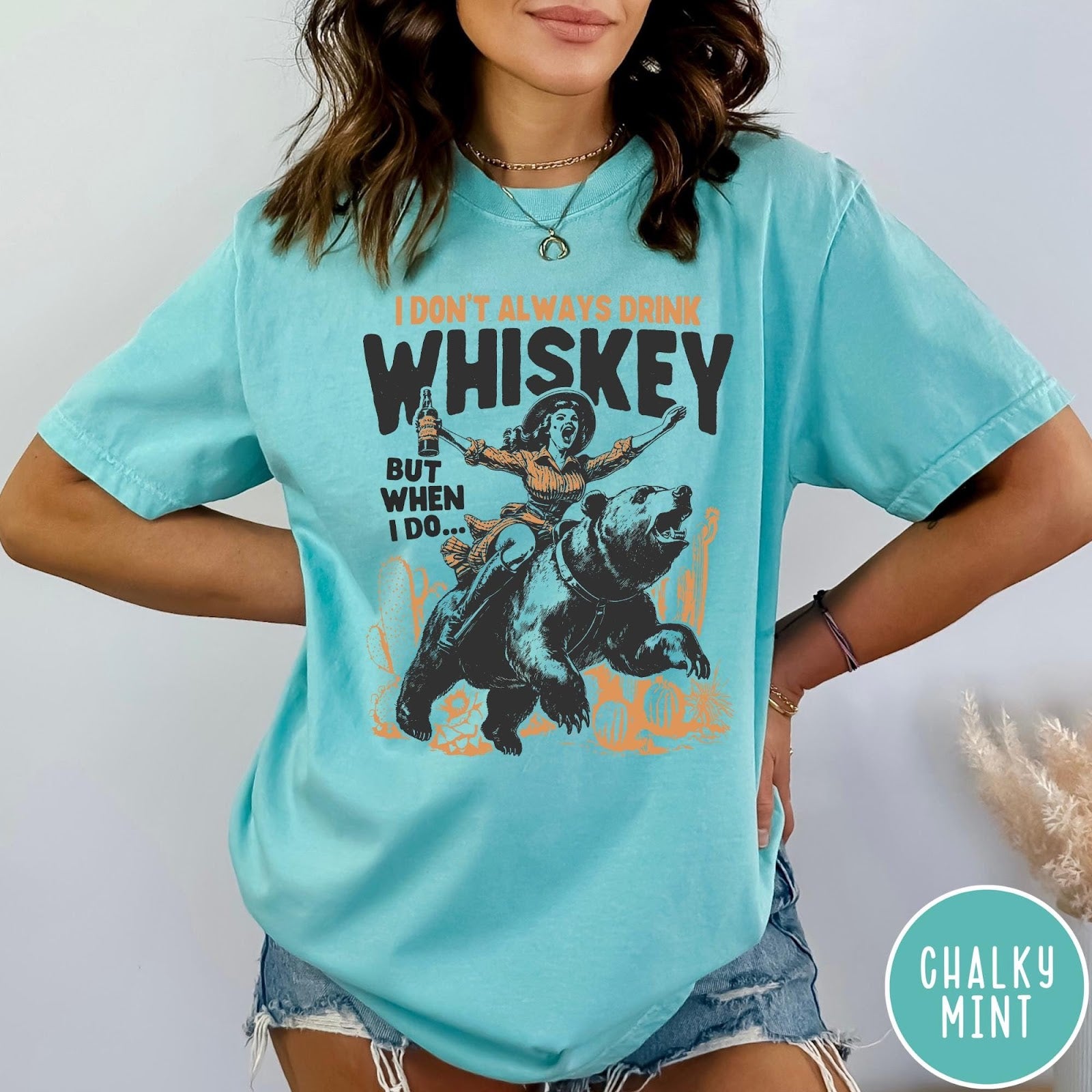 Comfort Colors tee in Chalky Mint featuring vintage style graphic of a woman riding a bear holding whiskey