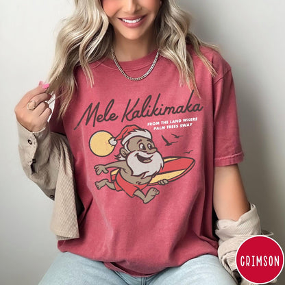 Comfort Colors tee in Crimson featuring vintage style graphic of a surfing Santa Claus on vacation