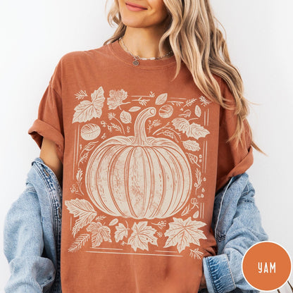 Comfort Colors tee in Yam featuring rustic pumpkin design with surrounding fall leaves and woodland elements