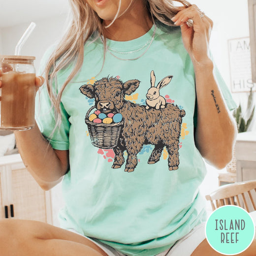 Comfort Colors tee in Island Reef featuring graphic style Highland cow and bunny with an Easter egg basket