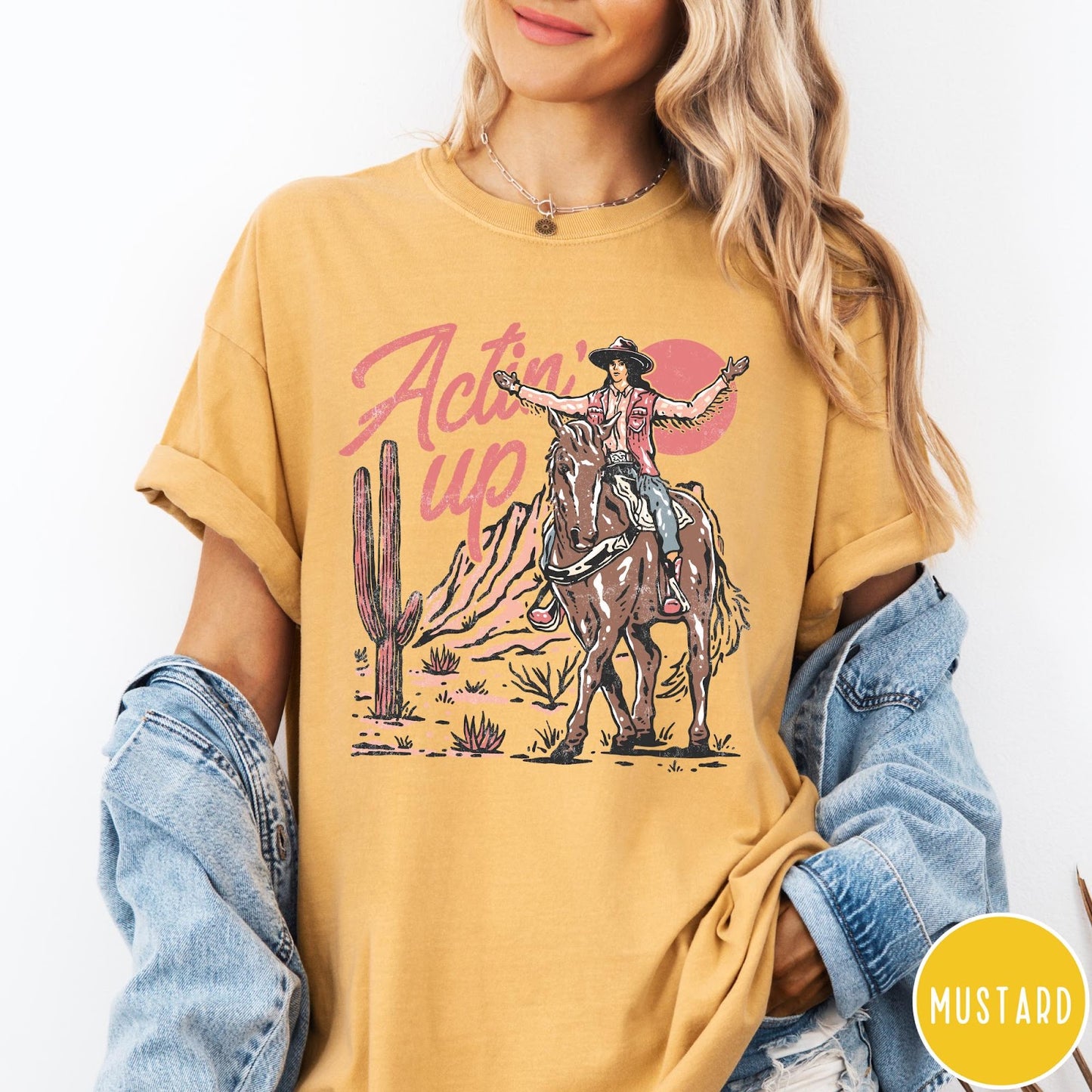 Comfort Colors tee in Mustard featuring western style graphic of a cowgirl riding a horse in the desert