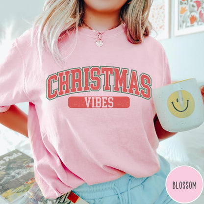 Comfort Colors tee in Blossom featuring Christmas holiday theme graphic with red and green text design