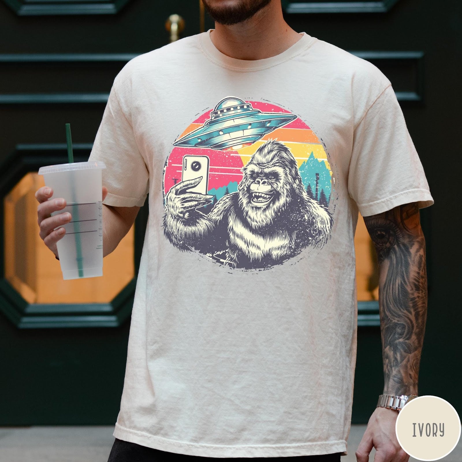 Comfort Colors tee in Ivory featuring retro graphic design of Bigfoot taking a selfie with a UFO