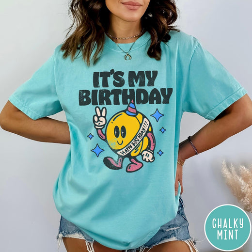 Comfort Colors tee in Chalky Mint featuring retro birthday mascot graphic with peace sign and party hat