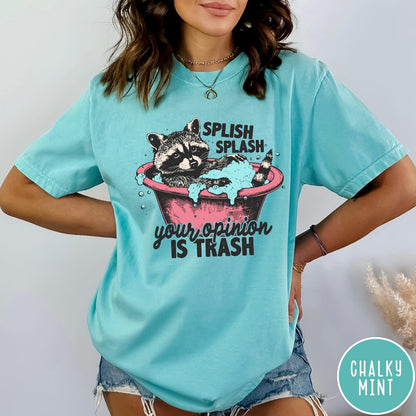 Comfort Colors tee in Chalky Mint featuring illustrative graphic of a raccoon sitting in a pink bathtub