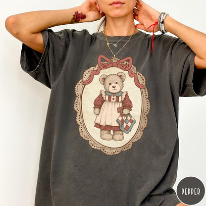 Comfort Colors tee in Pepper featuring vintage style teddy bear graphic inside a decorative lace oval frame