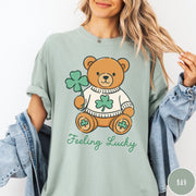Comfort Colors tee in Bay featuring cute teddy bear graphic wearing a sweater with shamrocks