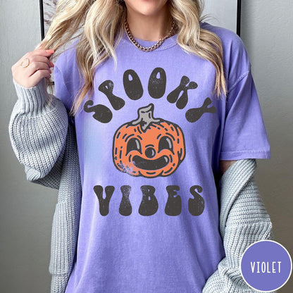 Comfort Colors tee in Violet featuring retro style graphic with a smiling pumpkin and Spooky Vibes text