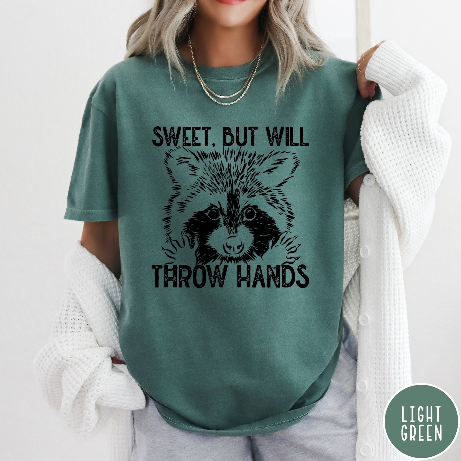 Comfort Colors tee in Light Green featuring graphic style raccoon illustration with text Sweet But Will Throw Hands