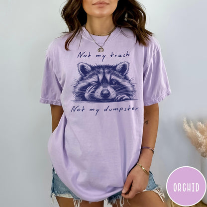 Comfort Colors tee in Orchid featuring illustrated style graphic of a winking raccoon with text not my trash