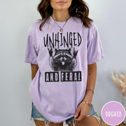 Comfort Colors tee in Orchid featuring graphic style raccoon with tongue out and rock and roll hands