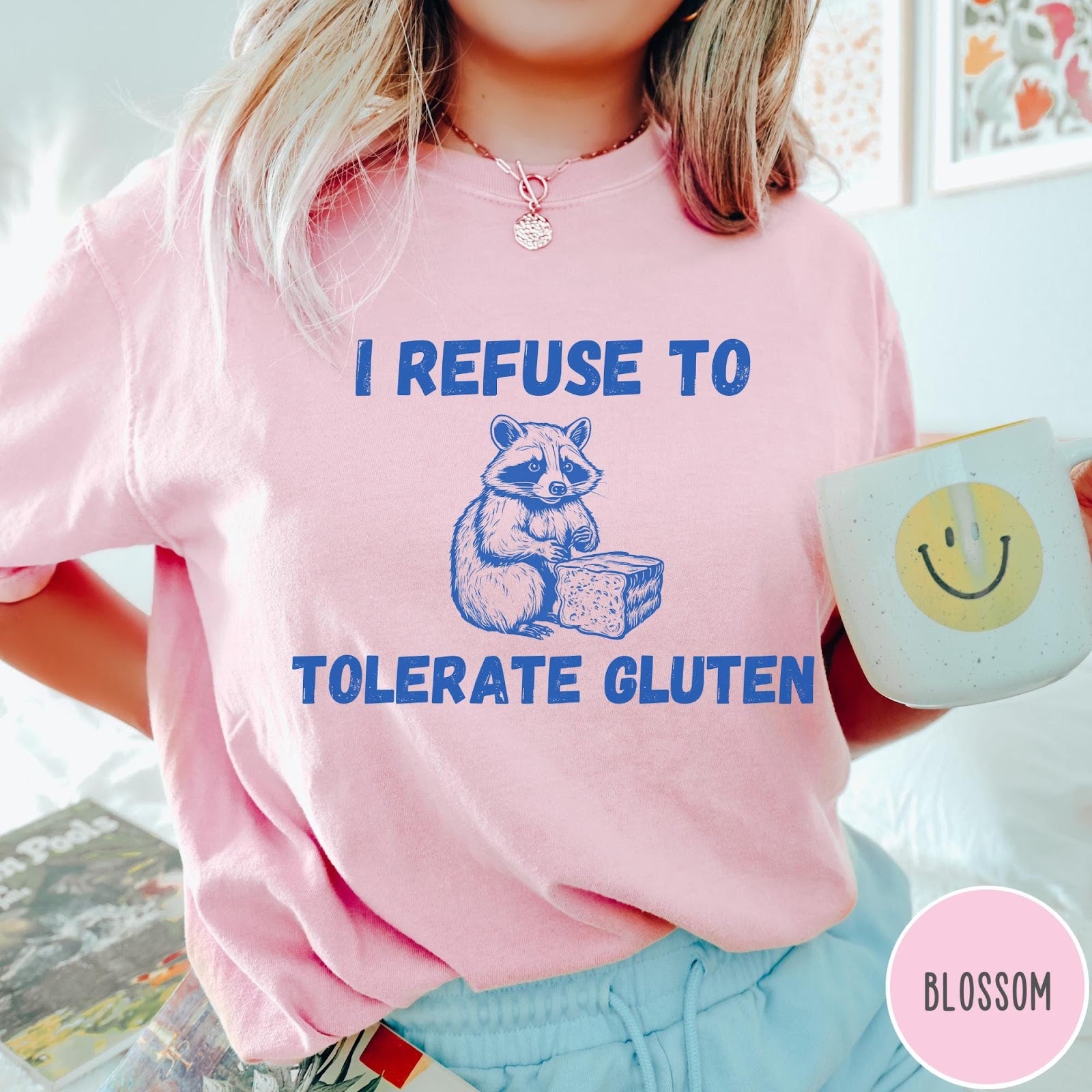 Comfort Colors tee in Blossom featuring graphic style illustration of a raccoon holding a loaf of bread