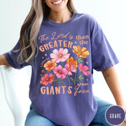 Comfort Colors tee in Grape featuring floral Bible verse graphic design with 1 John 4:4 scripture text