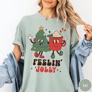 Comfort Colors tee in Bay featuring retro style graphic of a cartoon Christmas tree and cocoa mug