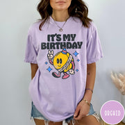 Comfort Colors tee in Orchid featuring retro birthday mascot graphic with peace sign and party hat