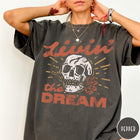 Comfort Colors tee in Pepper featuring vintage style skull graphic with Livin the Dream text design