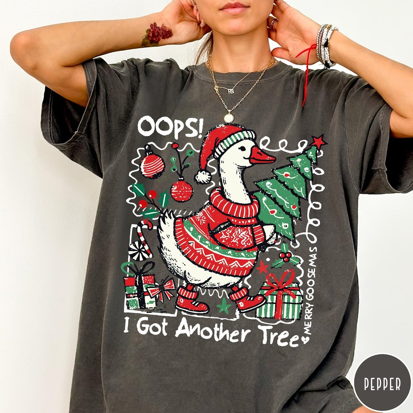 Comfort Colors tee in Pepper featuring festive goose graphic wearing a Santa hat and Christmas sweater holding tree