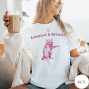 Comfort Colors tee in White featuring vintage style graphic of a standing raccoon with text Expensive and Difficult