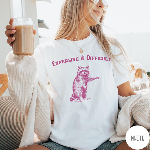 Comfort Colors tee in White featuring vintage style graphic of a standing raccoon with text Expensive and Difficult
