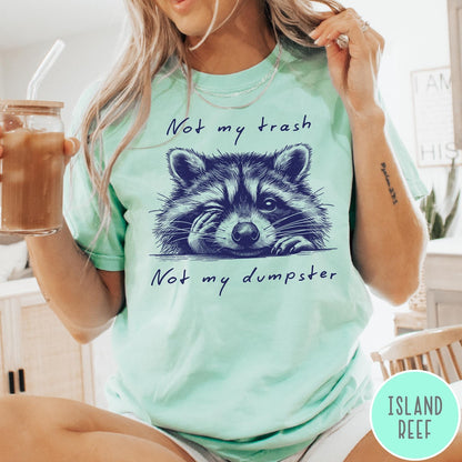 Comfort Colors tee in Island Reef featuring illustrated style graphic of a winking raccoon with text not my trash