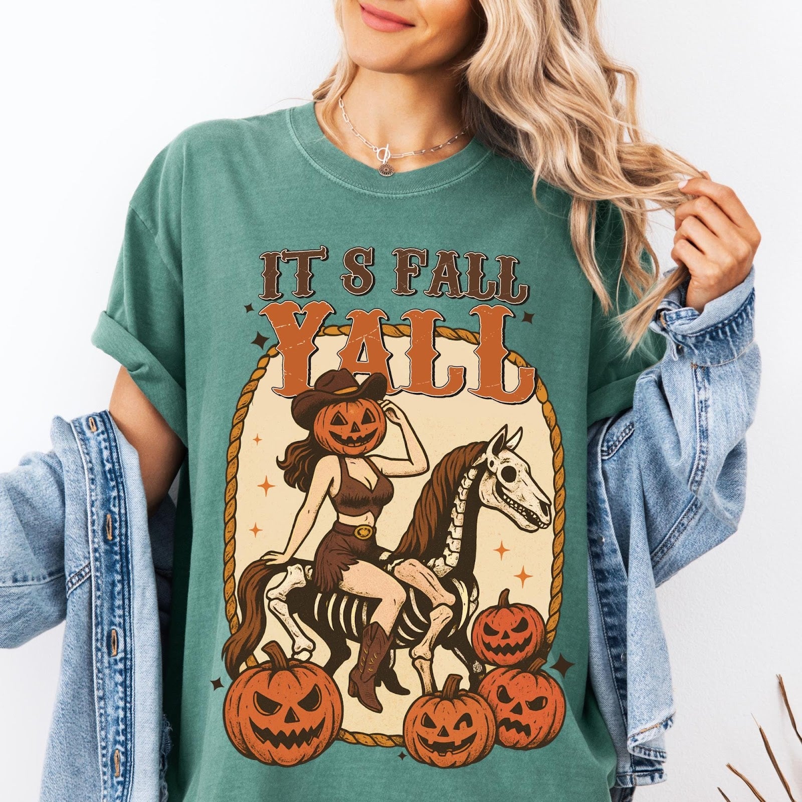 Comfort Colors tee in Sage featuring western graphic of a pumpkin cowgirl riding a skeleton horse with pumpkins