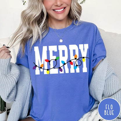 Comfort Colors tee in Flo Blue featuring festive holiday style graphic with Merry text and Christmas lights