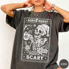 Comfort Colors tee in Pepper featuring graphic design of a skeleton in a Santa hat holding cocoa