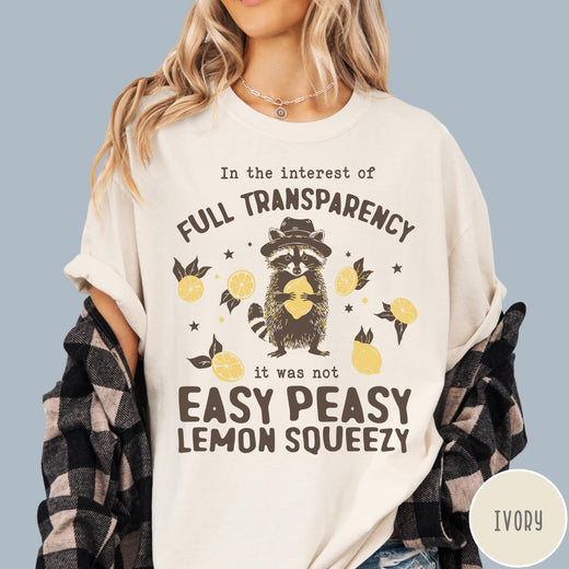 Comfort Colors tee in Ivory featuring graphic illustration of a raccoon wearing a hat holding a lemon