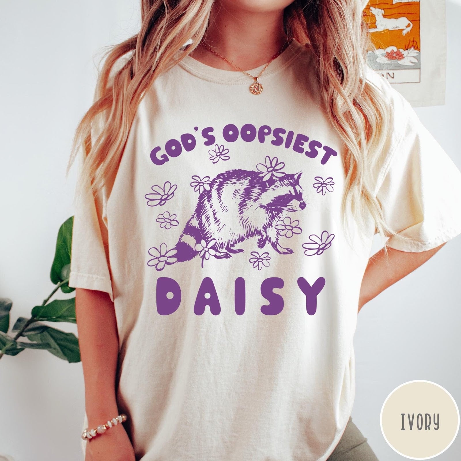 Comfort Colors tee in Ivory featuring whimsical raccoon graphic with daisy flowers and God's Oopsiest Daisy text