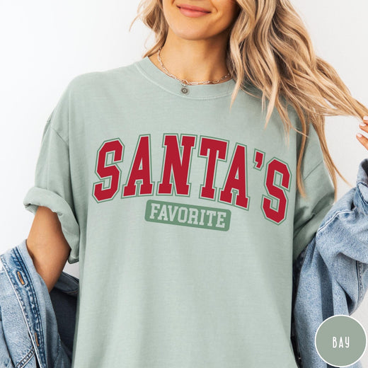 Comfort Colors tee in Bay featuring collegiate style Santa's Favorite Christmas graphic with red and green text