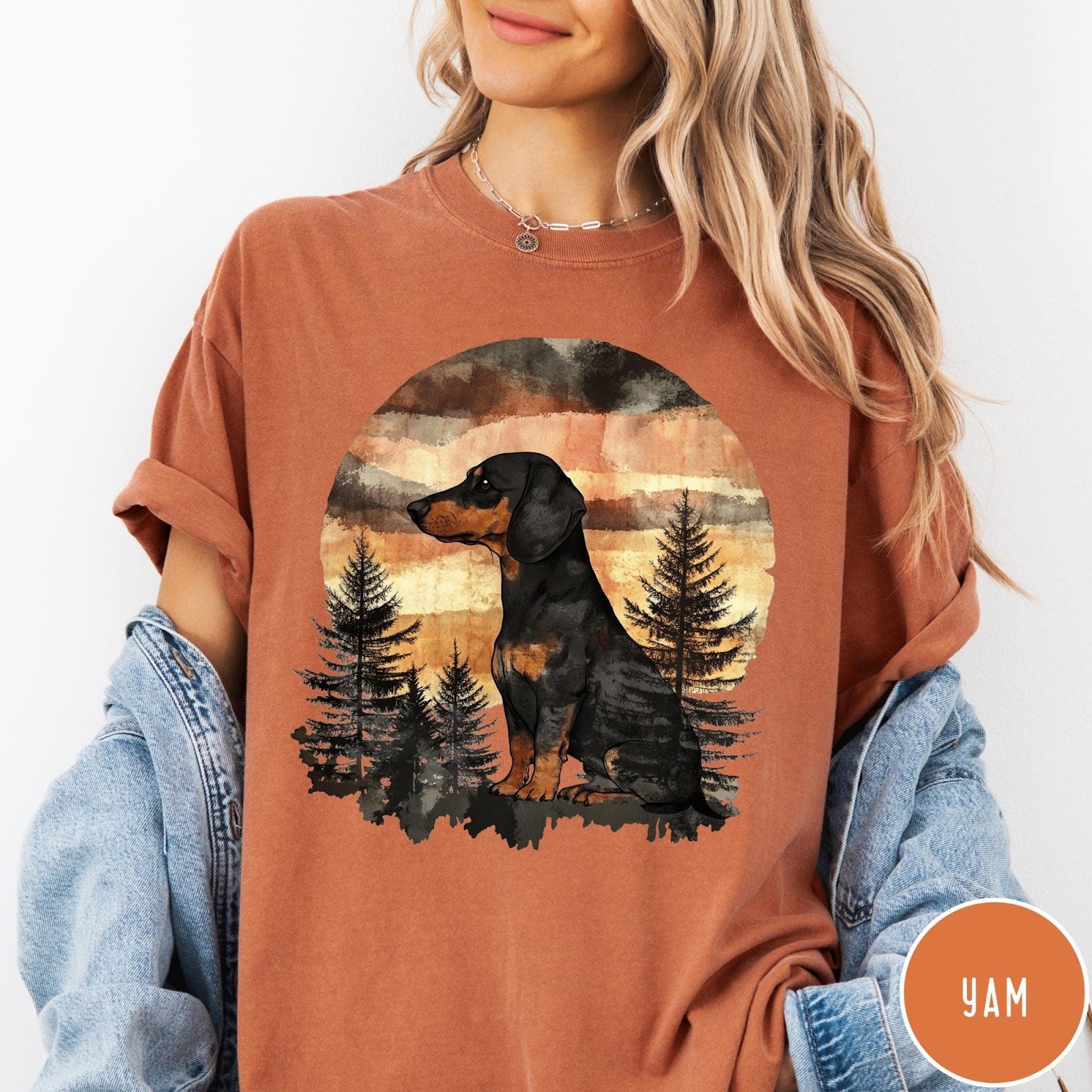 Comfort Colors tee in Yam featuring vintage style graphic of a dachshund sitting in a forest sunset