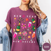 Comfort Colors tee in Berry featuring New Year celebration graphic with champagne bottles, glasses, and disco ball