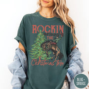 Comfort Colors tee in Blue Spruce featuring western graphic design of a cowboy on a bucking horse Christmas tree
