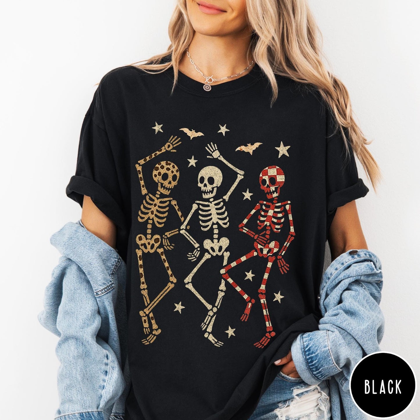 Comfort Colors tee in Black featuring dancing skeletons design with three skeletons, stars, and bats graphic