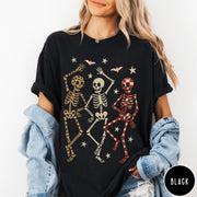 Comfort Colors tee in Black featuring dancing skeletons design with three skeletons, stars, and bats graphic